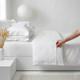 white-400-thread-count-sateen-100-percent-cotton-buttoned-duvet-cover-on-bed-hand-demonstrating-button-closure-detail-bedroom-lifestyle
