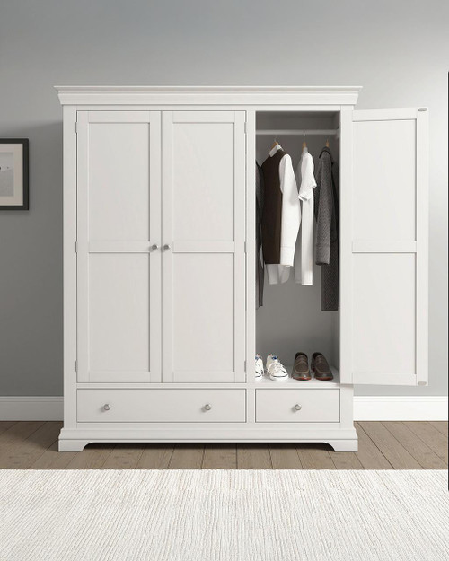Vermont 3 Door Wardrobe in Ivory VM100-101-235, with open doors revealing hanging clothes and a bottom shelf with shoes, in a modern bedroom setting.