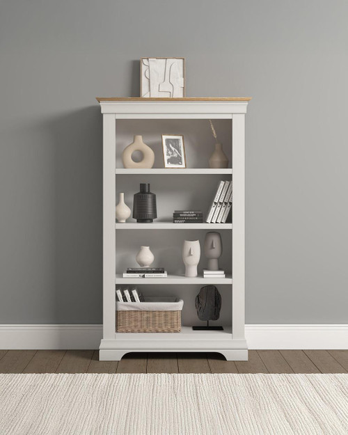 Vermont Bookcase in Ivory/Oak VM300-306-056, white wooden bookshelf with decorative items and books, against a gray wall. Vermont Bookcase in Ivory/Oak VM300-306-056, white wooden bookshelf with decorative items and books, against a gray wall.