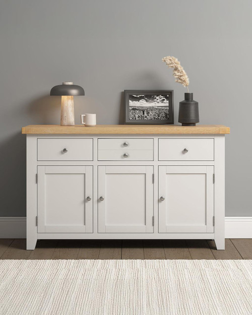 Hampton Ivory 3 Door 3 Drawer Sideboard HI400-405-051, modern white sideboard with natural wood top, featuring three doors and three drawers, placed against a gray wall.