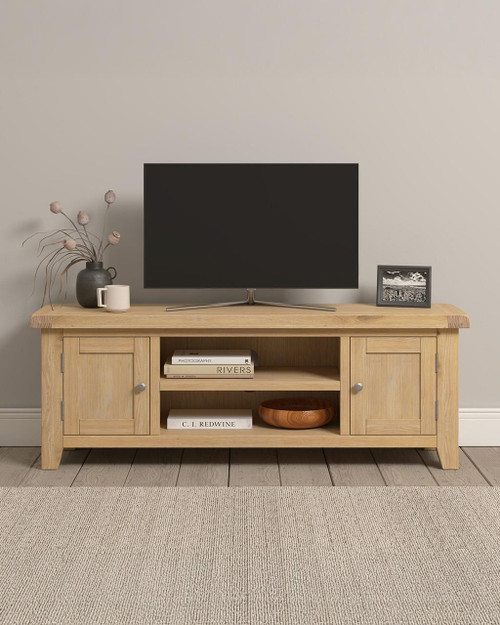 Hampton Oak Straight TV Unit HO300-305-067, modern light oak TV unit with storage cabinets and open shelves for media equipment, decorated with a TV, a vase with dried flowers, a coffee mug, a framed photo, books, and a wooden bowl. Hampton Oak Straight TV Unit HO300-305-067, modern light oak TV unit with storage cabinets and open shelves for media equipment, decorated with a TV, a vase with dried flowers, a coffee mug, a framed photo, books, and a wooden bowl.