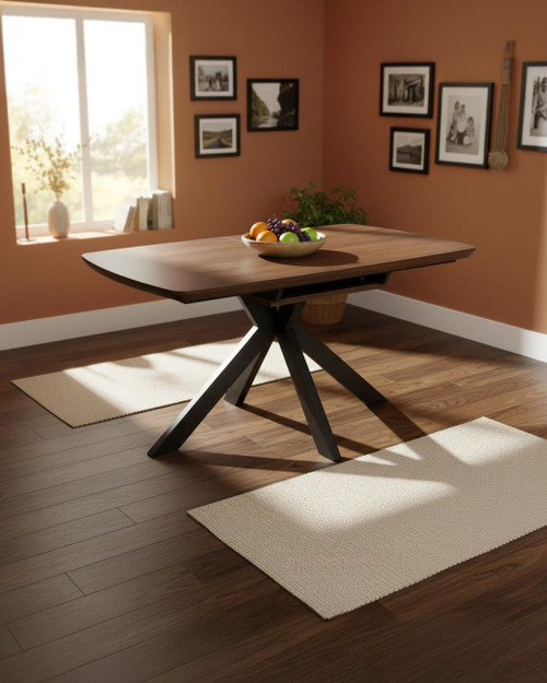 Hamilton Smoked Oak Extending Table 140cm - 180cm, a wooden extendable dining table with a smoked oak finish, located in a cozy dining room with peach walls and framed black-and-white photos.
