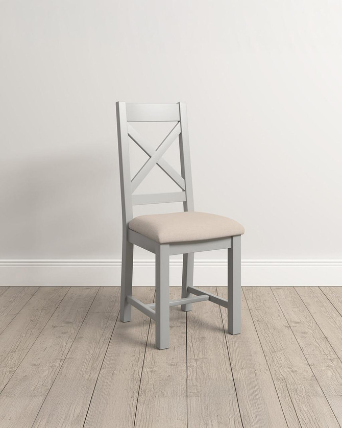 Hampton Pebble Grey Cross Back Chair, a grey wooden chair with a cushioned beige seat and a crisscross back design, shown as a single piece.