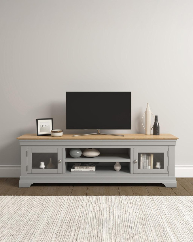 Vermont TV Stand in Pebble Grey/Oak VM300-305-061, a contemporary TV stand with pebble grey body, natural oak top, glass-paneled doors, and open shelves for media devices and storage.
