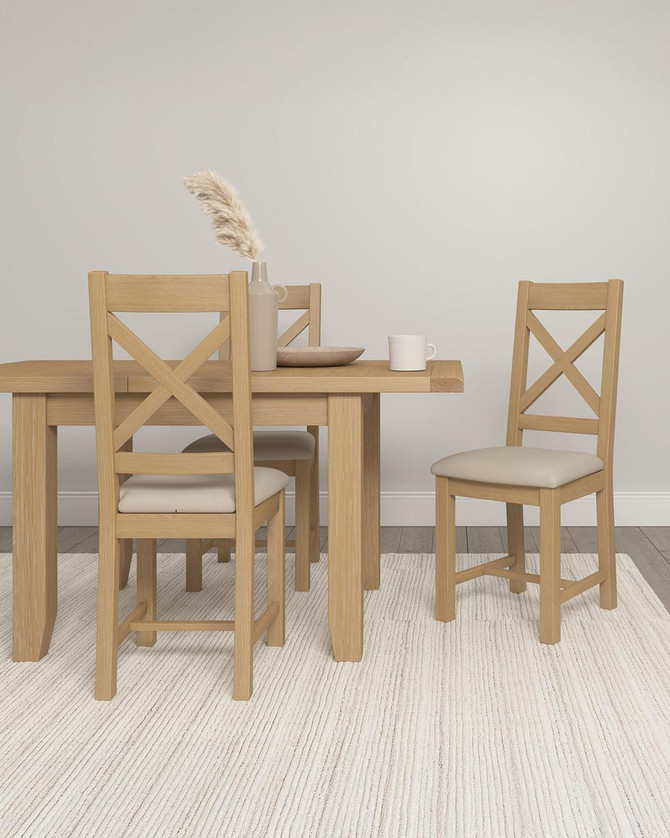 Hampton Oak Extending Dining Table HO400-403-075, wood dining table with extendable feature in a light oak finish, surrounded by matching wooden chairs with cushioned seats, set in a minimalist dining room with neutral decor.