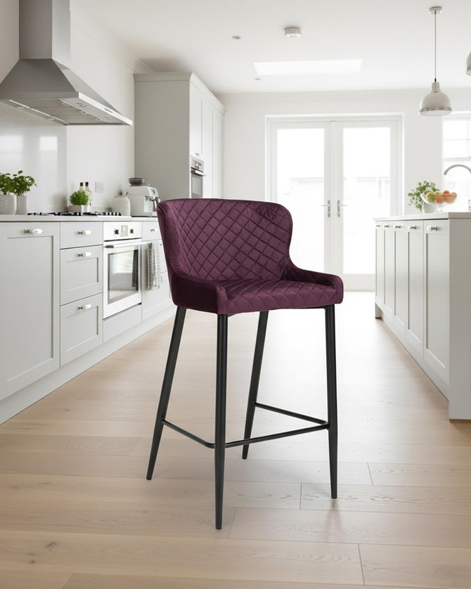 Roma Bar Stool in Mulberry, sold as a pair, with quilted velvet upholstery and black metal legs, in a modern kitchen setting.