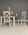 Hampton Ivory Extending Dining Table HI400-403-077, a light-colored wooden dining table with an extension feature, paired with white chairs with beige cushions, set in a minimalistic dining room with a gray wall and a beige rug.