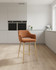 Stanley Rust Coloured Bar Chair, a tall bar-stool with a rust-colored upholstered seat and backrest, supported by light wooden legs in a modern kitchen setting. Stanley Rust Coloured Bar Chair, a tall bar-stool with a rust-colored upholstered seat and backrest, supported by light wooden legs in a modern kitchen setting.