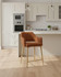 Stanley Rust Coloured Kitchen Counter Chair, pair of rust-colored upholstered chairs with wooden legs placed in a modern kitchen setting. Stanley Rust Coloured Kitchen Counter Chair, pair of rust-colored upholstered chairs with wooden legs placed in a modern kitchen setting.