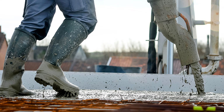 worker in rubber boots pouring concrete