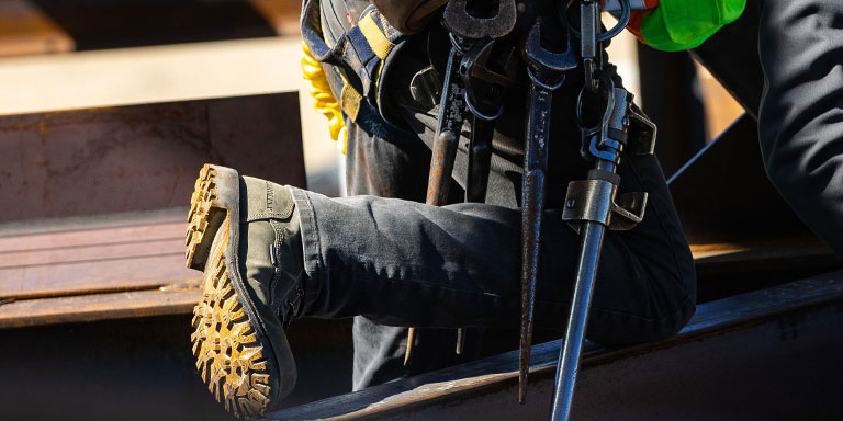 blue collar man in harness wearing Carolina pitstop boots