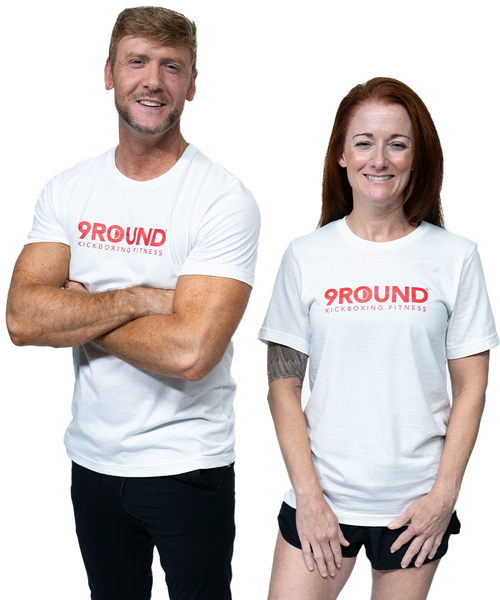 A man and woman standing side by side in matching white t-shirts that feature a red text logo that reads 9Round Kickboxing Fitness