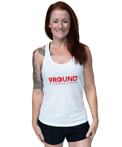 A woman in a white tank top with a red logo that reads 9Round Kickboxing Fitness on the front