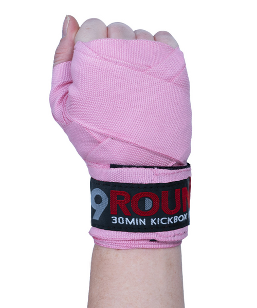 A hand held in the air in a fist with the palm of the hand facing you and wearing a solid pink boxing hand wrap A hand held in the air in a fist with the palm of the hand facing you and wearing a solid pink boxing hand wrap
