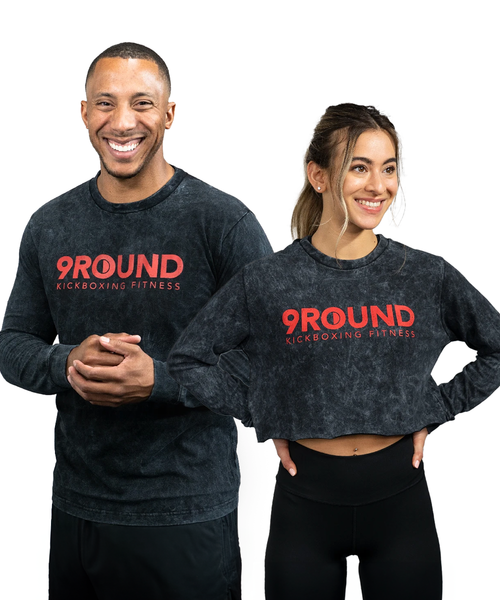 A young adult male and female in a long-sleeve black and grey acid wash t-shirt with a red 9Round logo on the front center