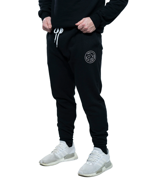 A bottom view of a pair of black joggers or sweatpants on a young adult male with a white circle 9Round logo