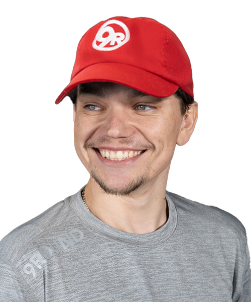 a young male wearing a red classic ball cap with a white 9Round circle logo 