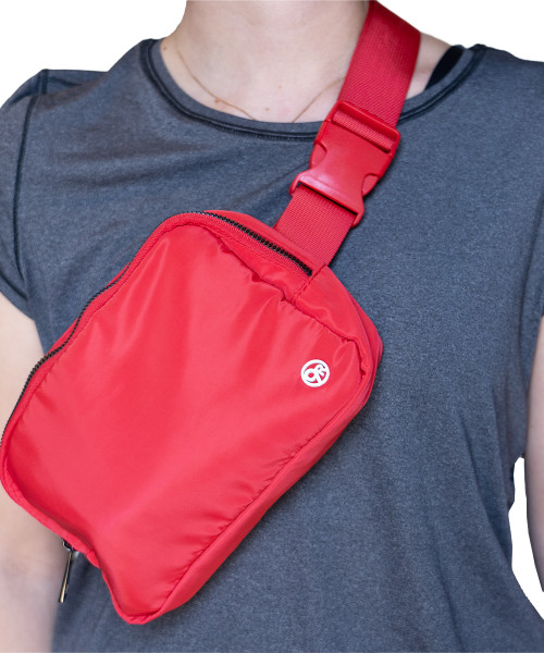 A close up of a girl wearing a grey t-shirt with a bright red belt bag across her chest. The belt bag has a small, metal 9Round circle logo in white on the front