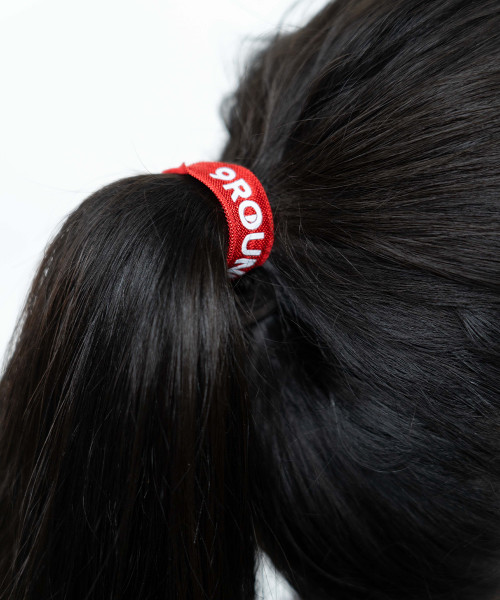 A woman with black hair tied up in a red 9Round yoga hair tie