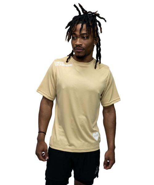 A man with dreadlocks wearing a gold short-sleeve athletic shirt and black shorts stands against a plain white background.