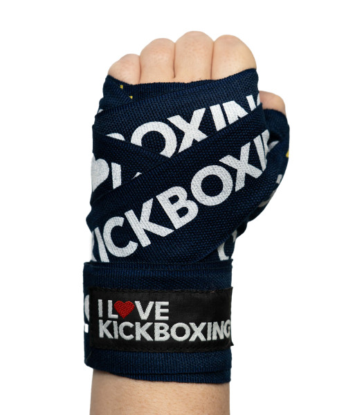 A hand wrapped in navy blue boxing wraps with KICKBOXING printed on them and a black patch stating I LOVE KICKBOXING.