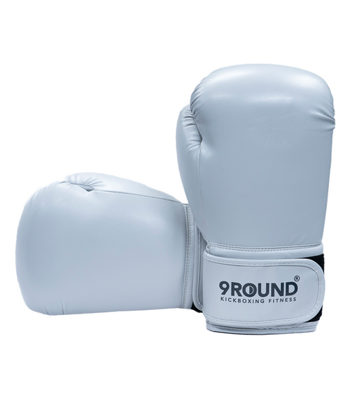 A pair of light gray boxing gloves with a 9Round Kickboxing Fitness logo on the wrist strap, positioned on a plain white background.