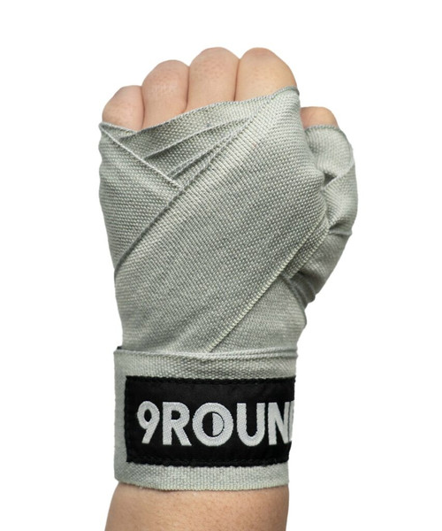 A hand wrapped in gray boxing hand wraps with a visible 9ROUND logo on the wrist.