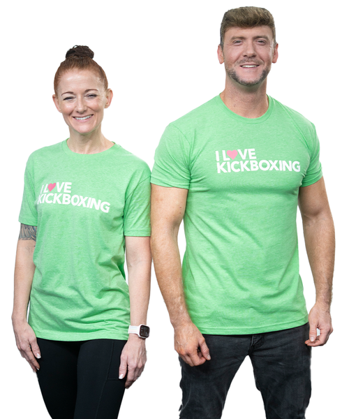 A man and a woman standing side by side smiling at the camera and wearing a green I Love Kickboxing t-shirt