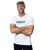 A man standing with his arms crossed wearing a white t-shirt that has a black logo that reads 9Round Kickboxing Fitness