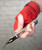 A person's hand wrapped in red boxing hand wraps holding the silver metal handle of a jump rope