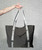 An arm out holding a grey tote bag with white and grey straps that have the 9Round logo all over
