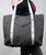 a grey tote bag with white and grey straps that have the 9Round logo all over