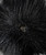 A close up view of a snap closure on a black pom pom that detaches from a black beanie hat