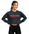 A young adult woman in a long-sleeve, cropped, black and grey acid wash t-shirt with a red 9Round logo on the front center