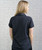 A back view of a young adult woman in a black polo shirt