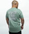 The back of a young adult male wearing a sage green t-shirt with a graphic text that reads, "Respect Every Strike," with a 9Round logo beneath the text.