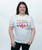A woman with brown hair smiling and wearing a white t-shirt that reads, "In my kickboxing era," in a fun yellow, red, and grey bubble text design with an I Love Kickboxing heart logo underneath.