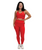 Woman standing and smiling, wearing a matching red sports bra and leggings set with white sneakers, on a plain white background.