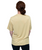 Person with hair in a low bun, wearing a light gold short-sleeve shirt and black pants, shown from the back against a white background.