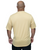 A man with a shaved head is standing with his back to the camera, wearing a light gold short-sleeve shirt and black pants against a white background.