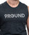 Person wearing a sleeveless dark gray shirt with the word 9ROUND in white striped letters on the front.
