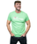 A man smiling off to the side of the camera wearing a green I Love Kickboxing t-shirt
