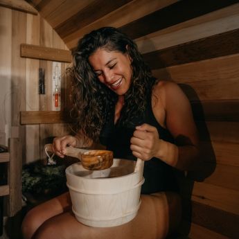 Woman enjoying the bucket and ladle in her Redwood Outdoors sauna