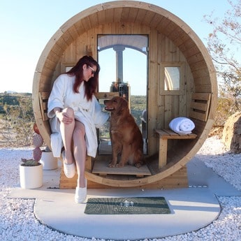 Lady and Her Dog sitting on the porch of their Redwood Outdoors Panorama Sauna