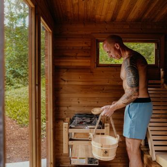 Man adding steam to his Redwood Outdoors sauna