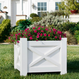 Main Street planter planted with red flowers on a lawn in front of a white home