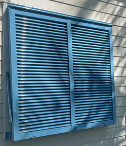 Blue Bahama Shutter installed on a home in a closed position Blue Bahama Shutter installed on a home in a closed position
