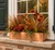 Real Copper Liner or window box with autumnal flowers on a ledge with a home with shutters.