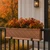 La Fleur fiberglass window box coated with liquid copper filled with fall foliage on a railing in front of a home