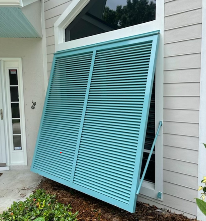 Hurricane Rated Bahama Shutter in teal on a cream colored home